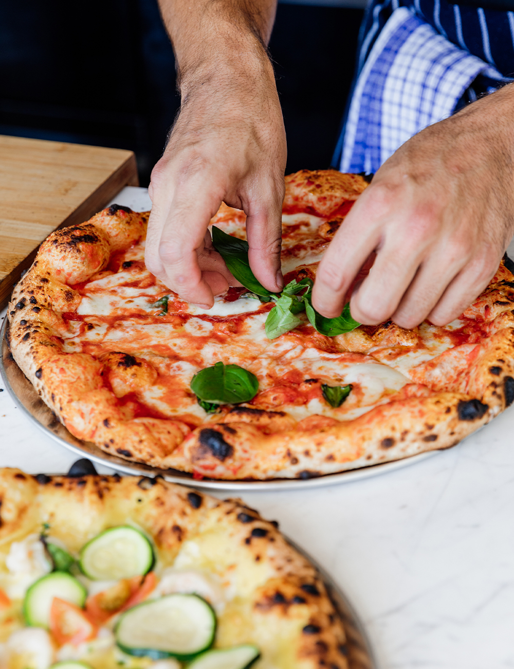 a chef putting toppings on a pizza