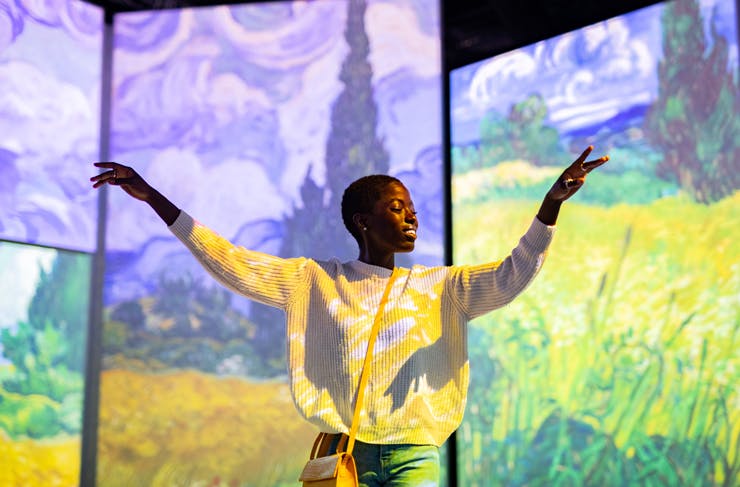 A person dancing in front of Van Gogh paintings projected on to large screens for Van Gogh Alive Sydney
