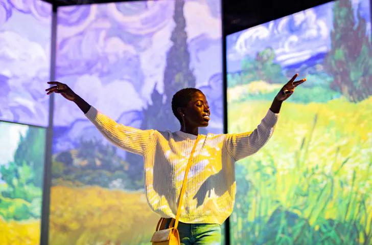 A person dancing in front of Van Gogh paintings projected on to large screens for Van Gogh Alive Sydney