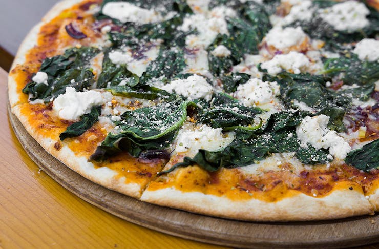 A delicious close up of a vegetarian pizza on a board.