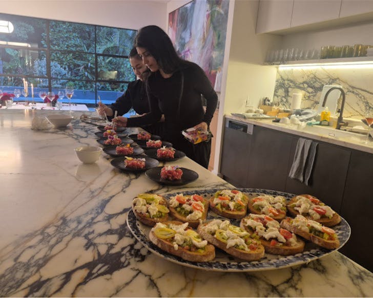 Two women put together a dish for a dinner party