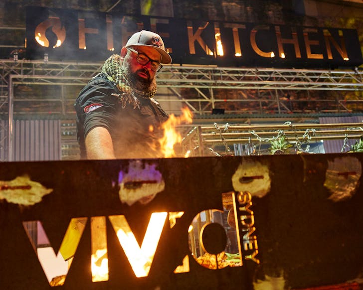 a pitmaster cooks over fire at the vivid food kitchen