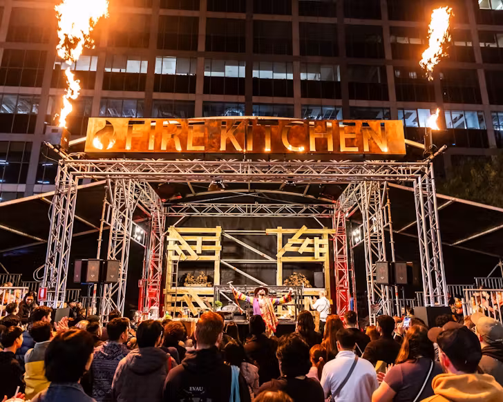 the main stage with flames surrounding a performer at vivid fire kitchen, returning in 2025