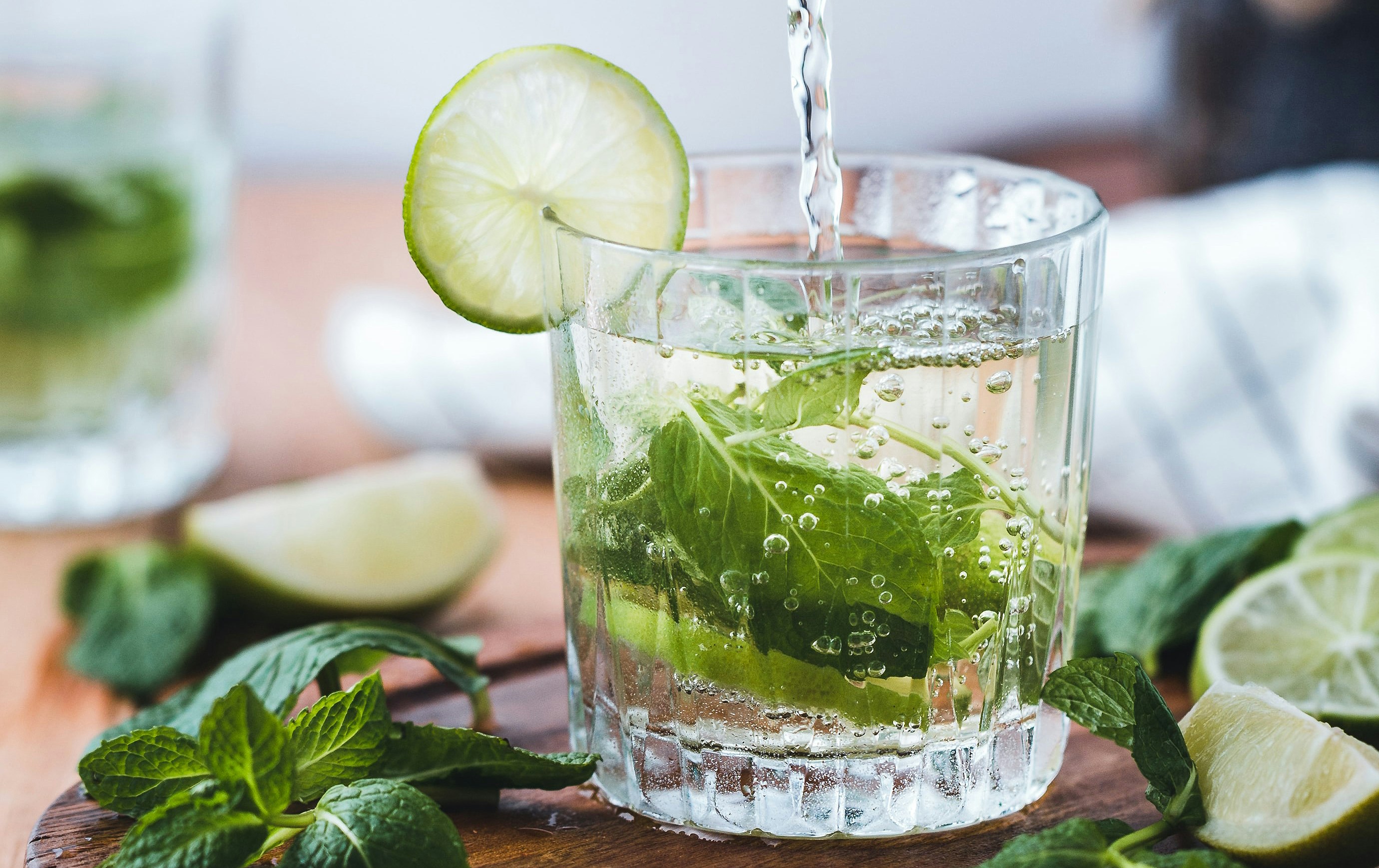 A glass of vodka with lime and other green leaves