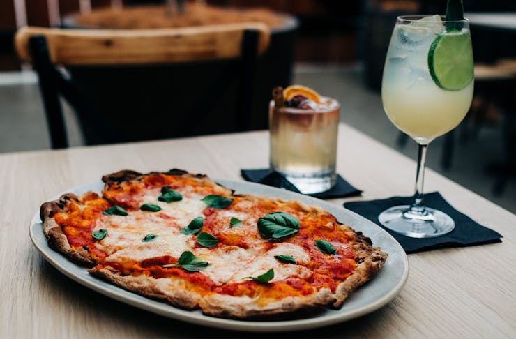 a pizza and two different cocktails on a table