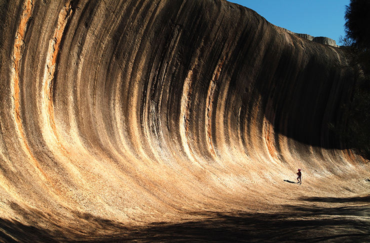 A traveller exploring the mammoth wave rock in Western Australia.