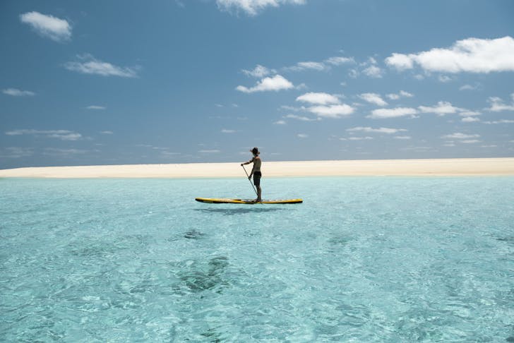 a person stand up paddle boarding at a beach near Broome