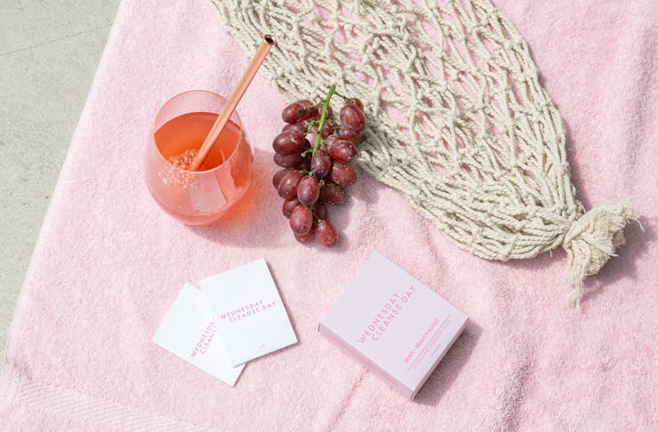 a pink drink and packets of powder on a pink towel