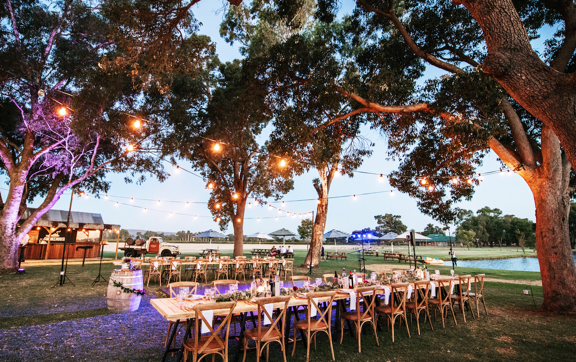 Long table setup under gumtrees and fairy lights