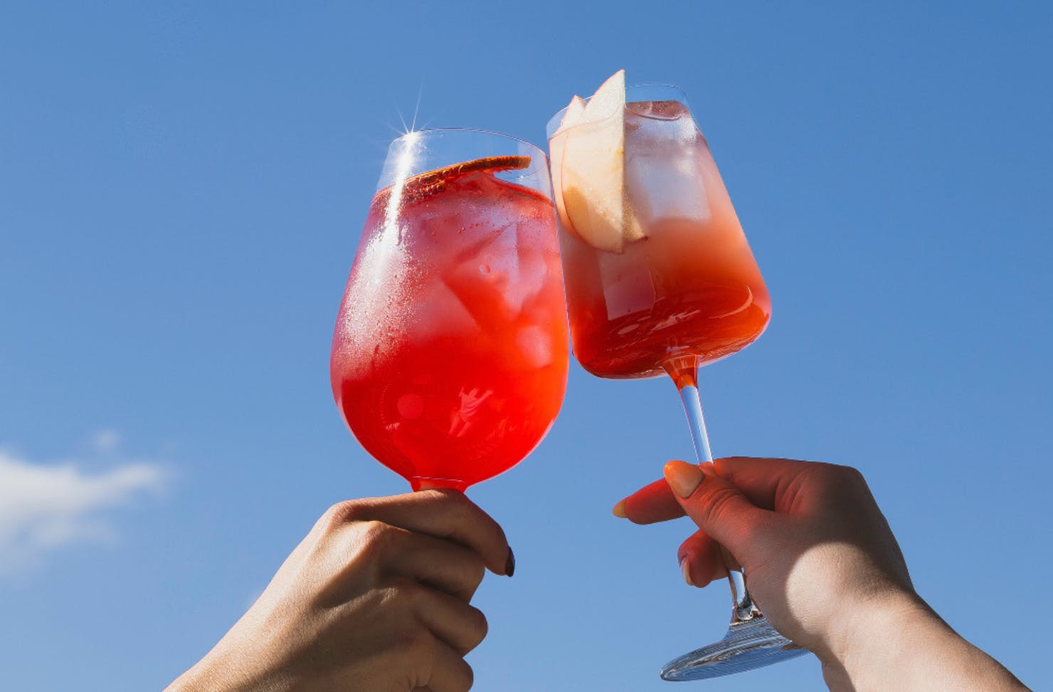 cocktails being held up to a blue sky at the beverly rooftop in melbourne 