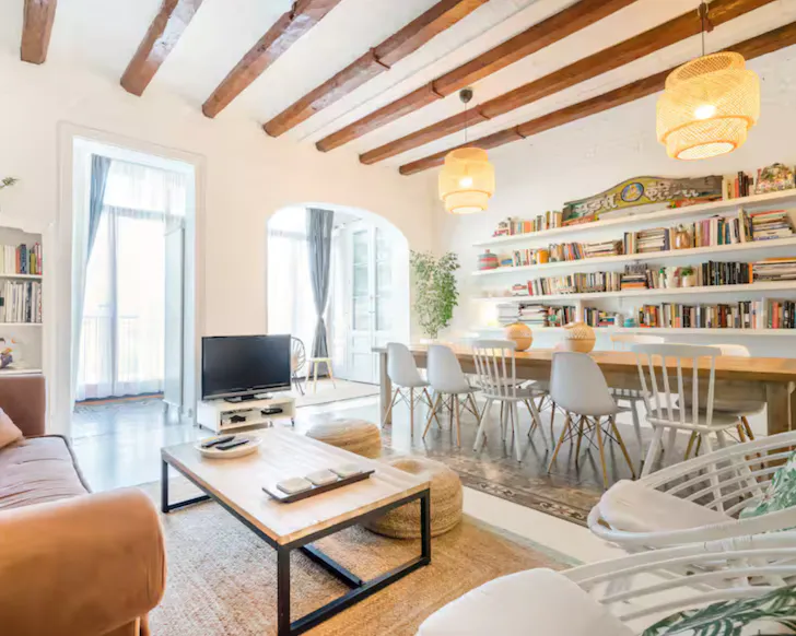 Sunlit living area with a floor-to-ceiling library in a Barcelona Airbnb.