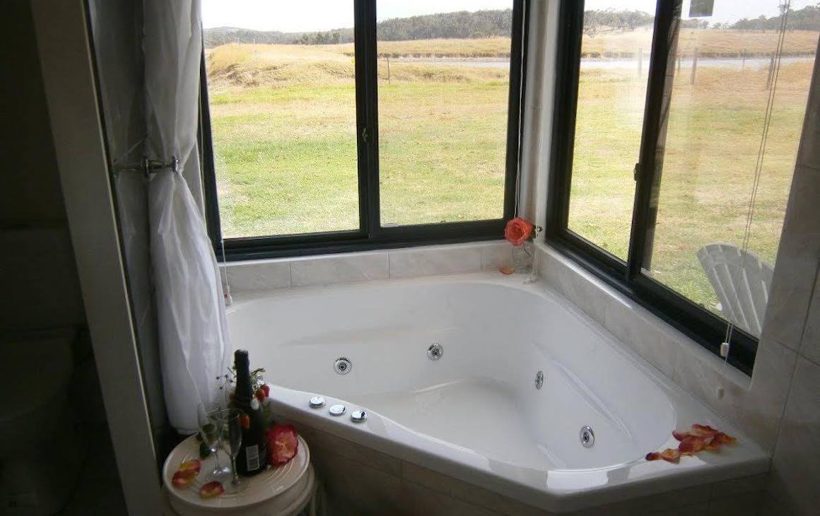 a corner spa bath with windows looking out onto farmland
