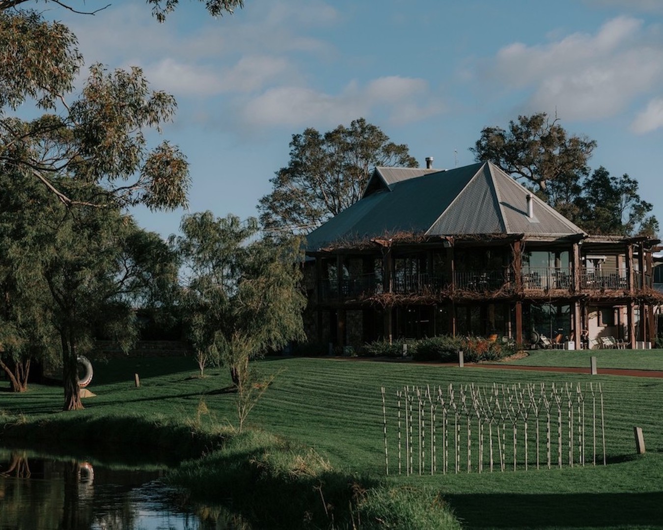 A lush winery in Margaret River, with grass, trees and vines surrounding a picturesque building