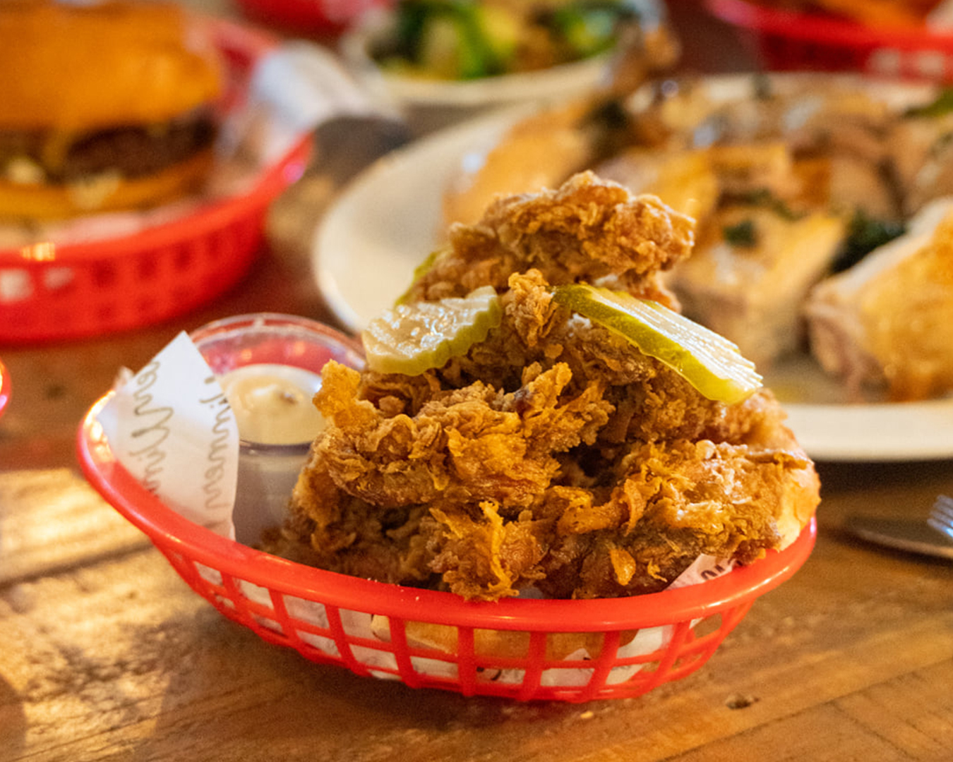 A basket of chicken with pickles on top.