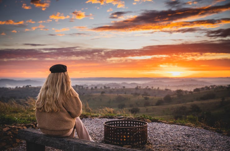 A woman in warm clothing watching the sunset over Mudgee NSW