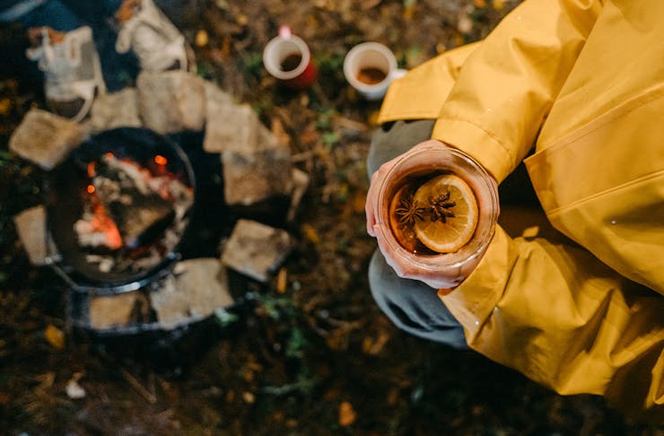 a person holding a mug of mulled wine by a fire