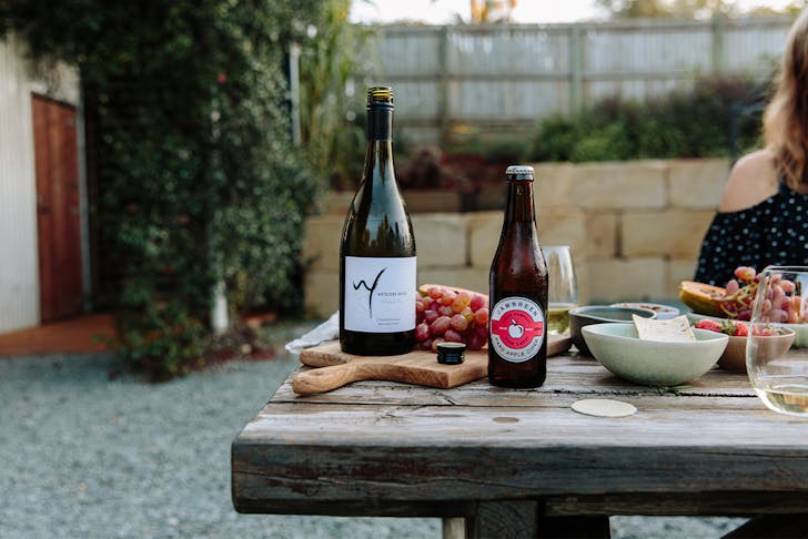 A bottle of wine and cider on a table with plates and boards