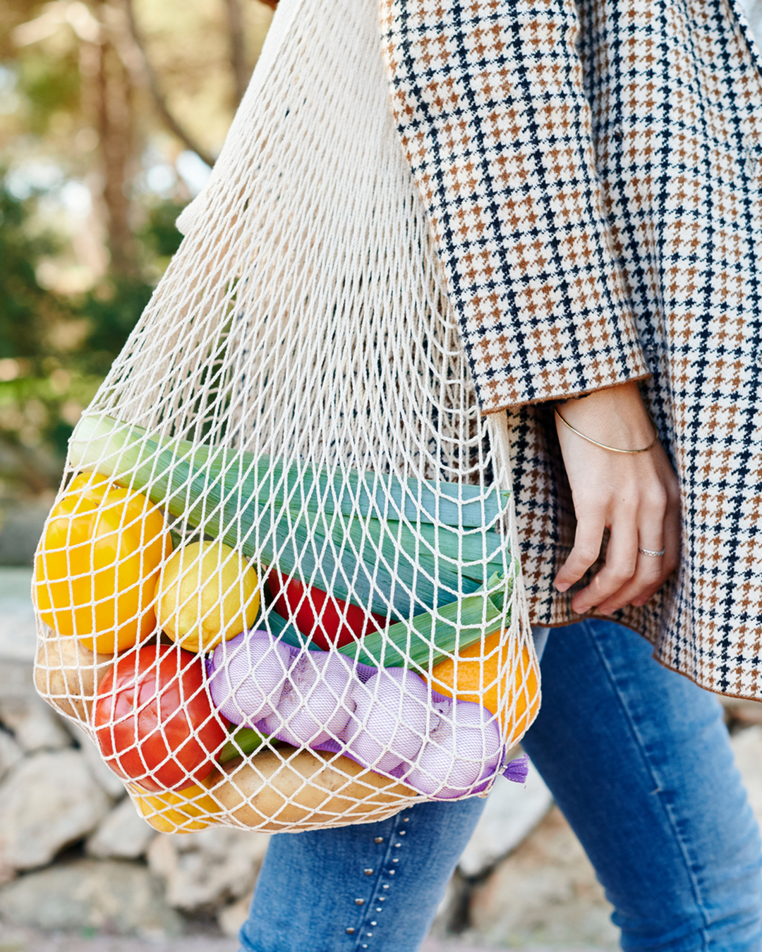A woman walks with a reusable bag.