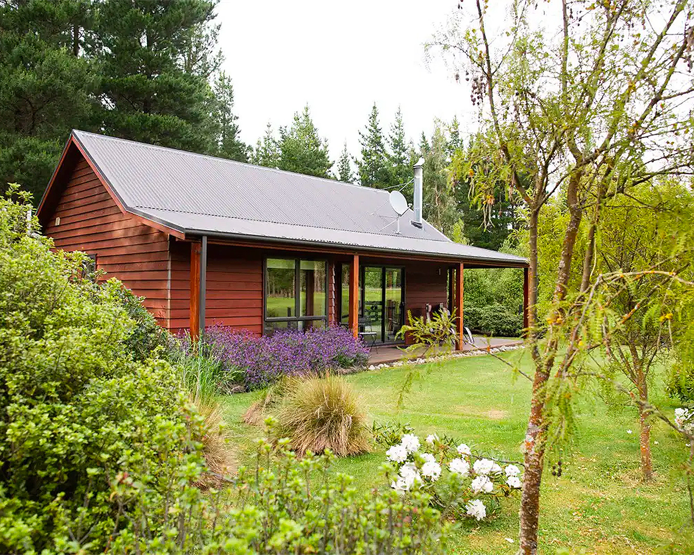 A cute, fairytale-like cottage hidden amongst tall trees in one of the best places to stay in Hanmer Springs. 