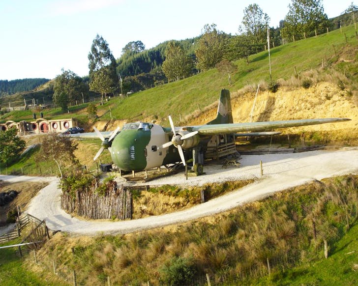A war plane with a hobbit house in the background.