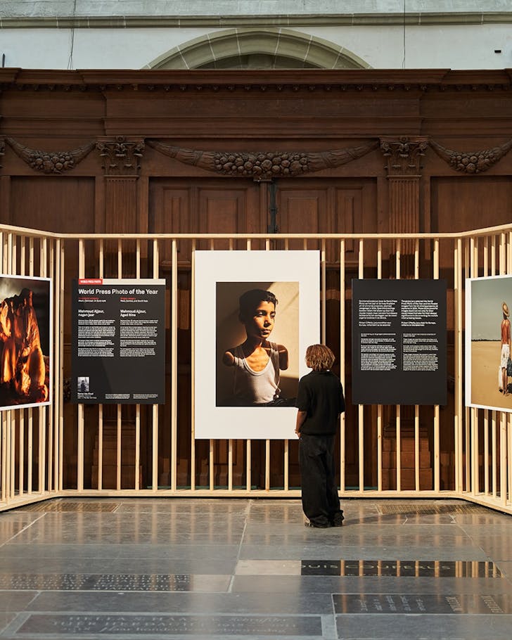 Some persuses the World Pres Photo exhibition in a large hall.