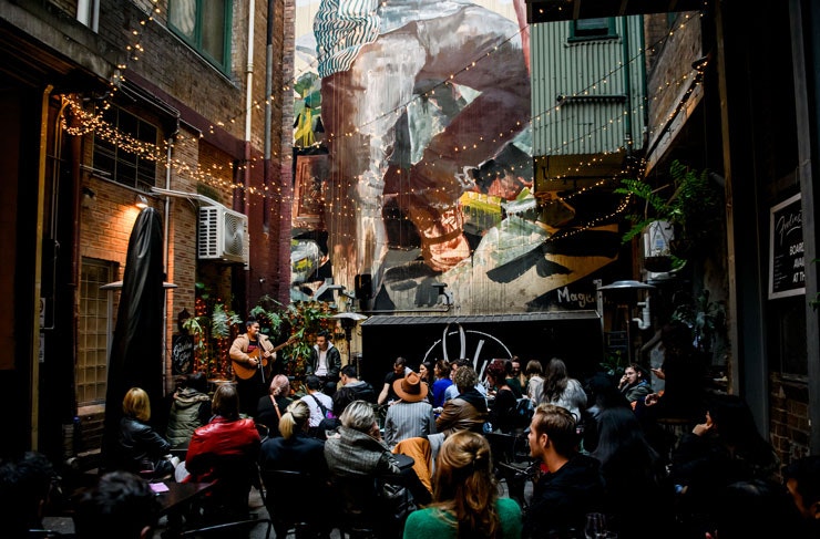 People gathered in a laneway watching live music. 