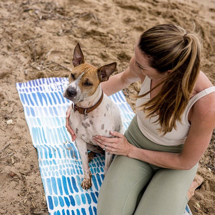 a person and a dog on a colourful yoga mat