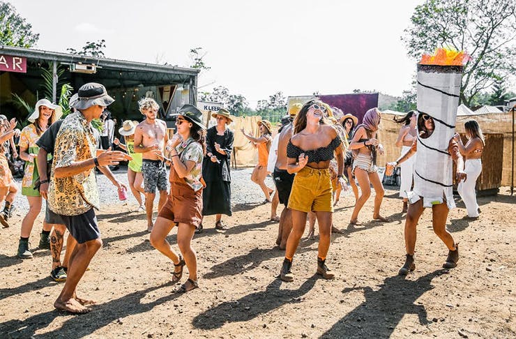 A group of young people dancing at an outdoor festival.