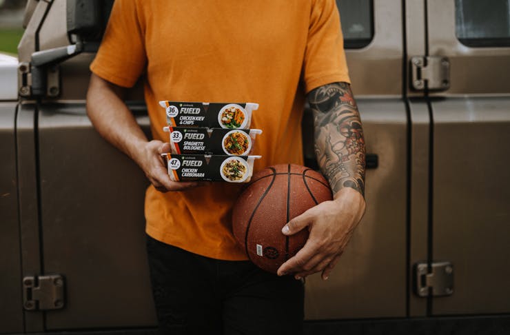 A person holding a basket ball and some Youfoodz ready made meal packs
