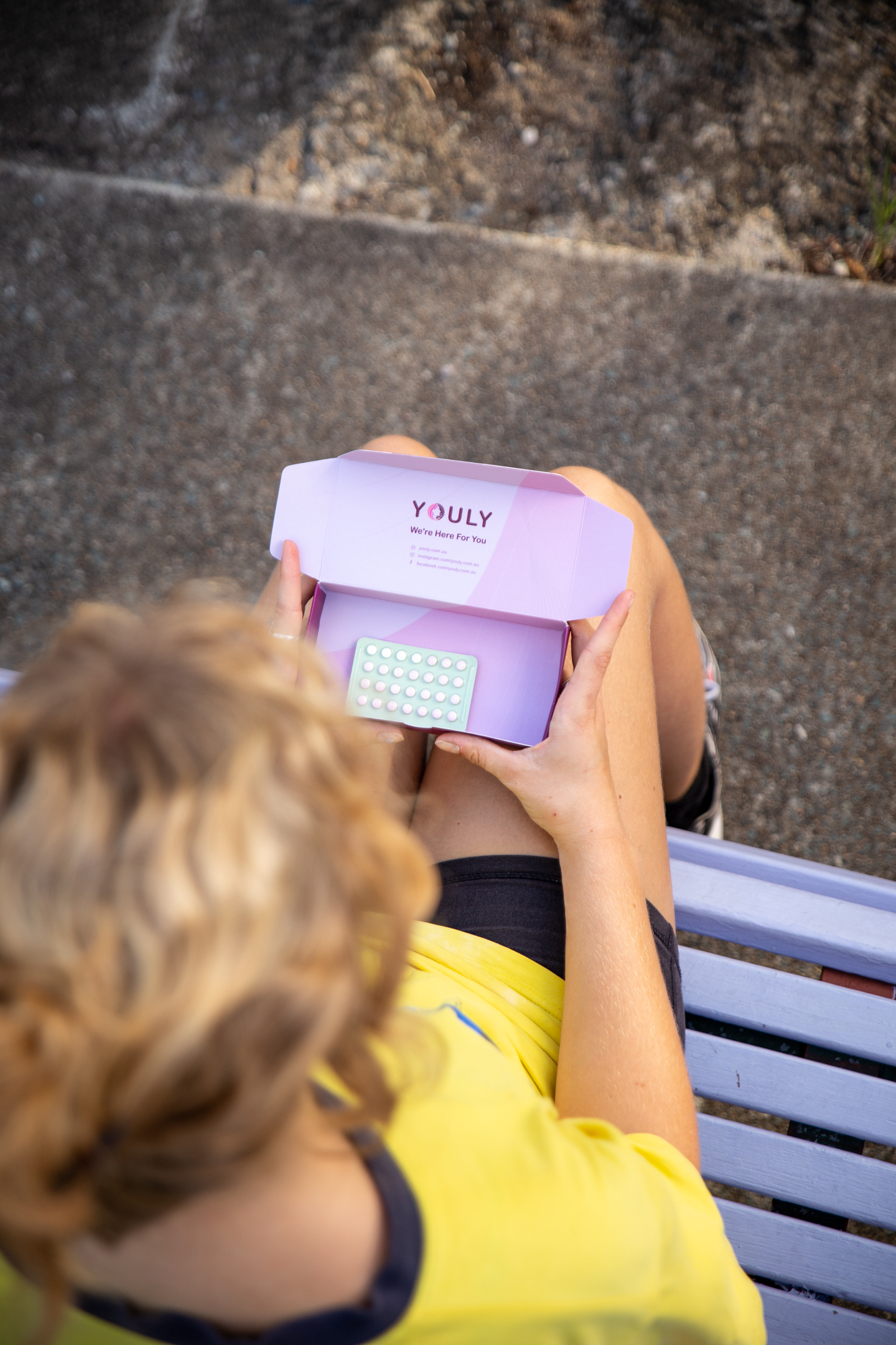 a woman on a bench opening a small box of contraceptive