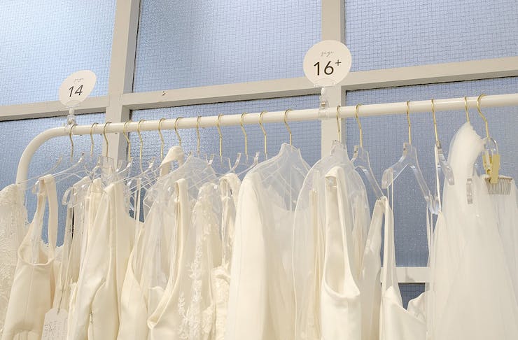 Bridal dresses hang on a rack.