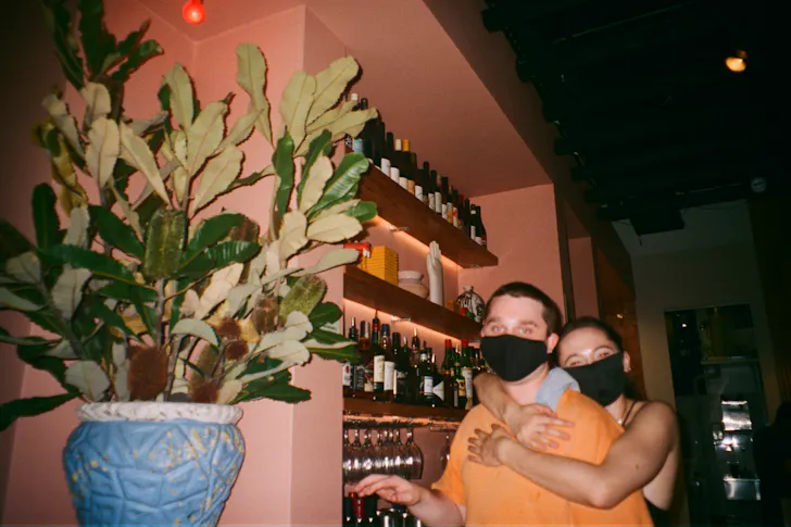 two people wearing face masks in a bar