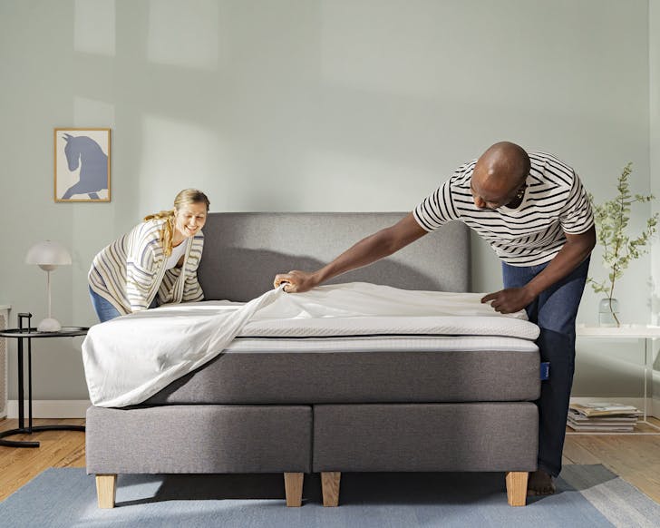 Two people making a bed that features the Emma Diamond Hybrid Mattress