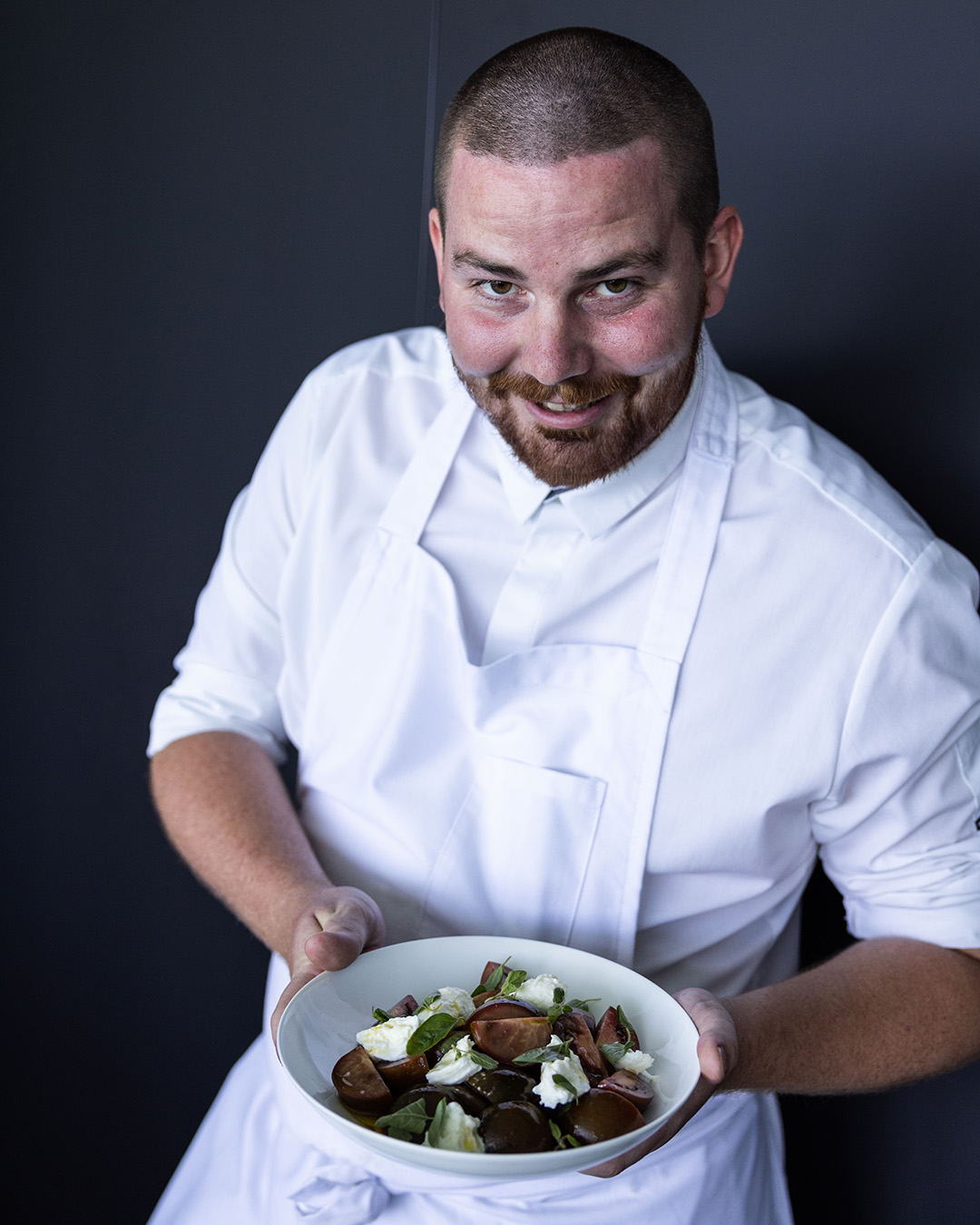 Alex Prichard head chef at Bondi Icebergs holding a Caprese salad