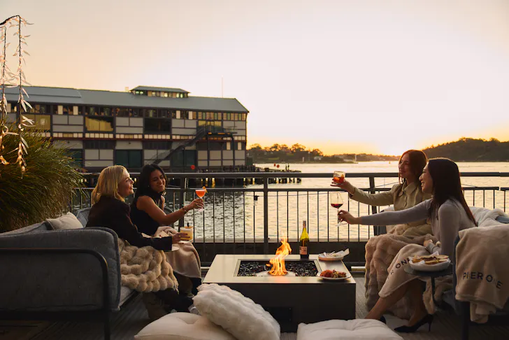 people sitting by the harbour at sunset