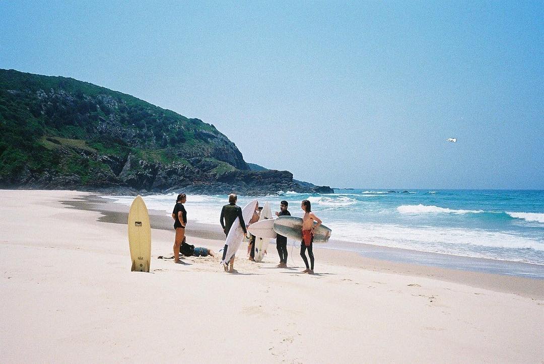 a group of surfers standing on a beach