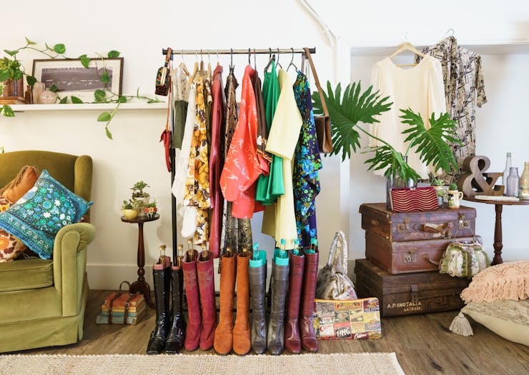 A clothing rack stacked with colourful vintage clothing in a vintage decorated room.