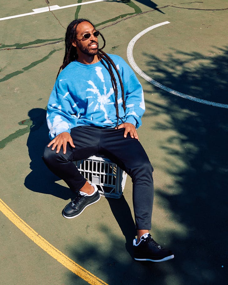 Kid Fiction sitting on a milk create in a tennis court