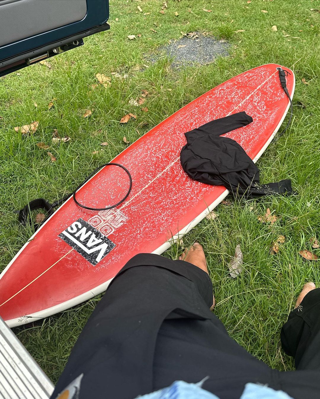 a surfboard and wetsuit on the grass