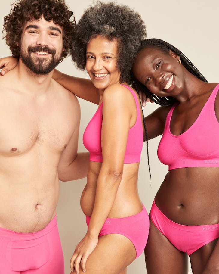 Three people wearing bright pink Boody bamboo undies and bras for Breast Cancer Awareness Month