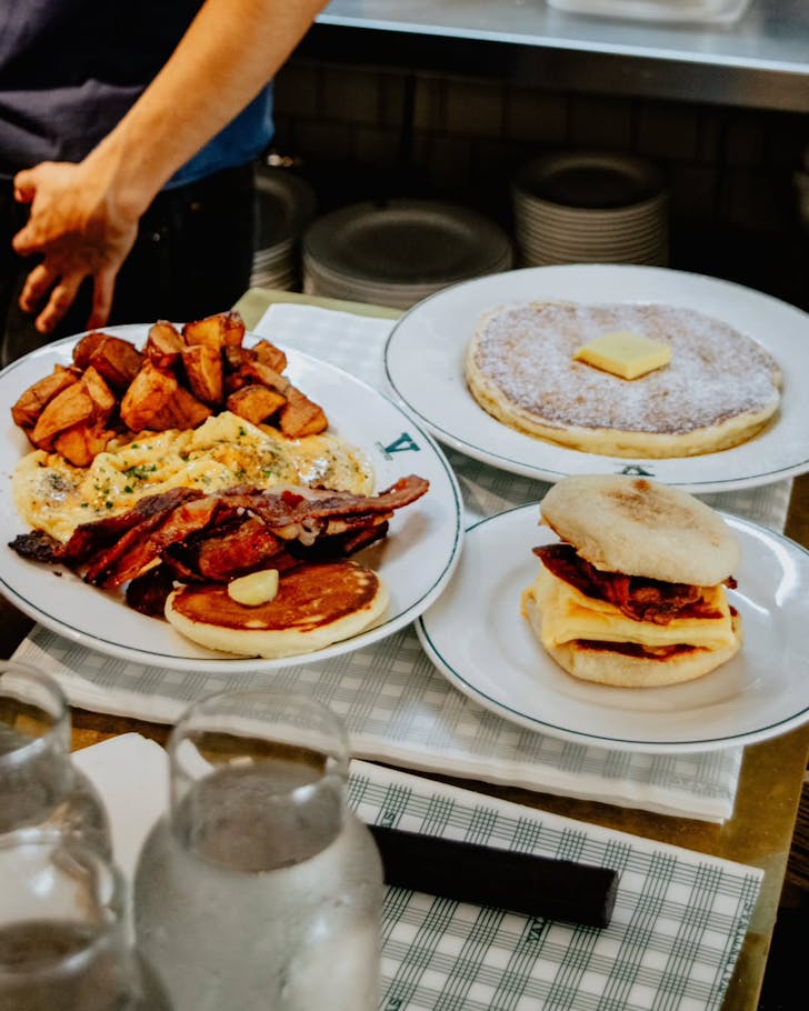 plates of bacon, pancakes, potatoes and a muffin at sydney cafe valentinas