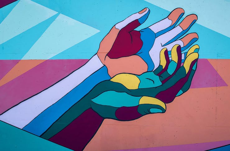 a set of multi-coloured hands is painted on a wall.