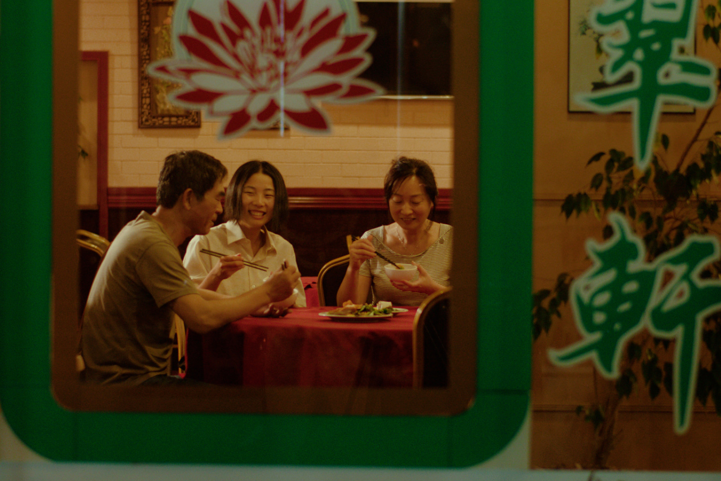 three people sitting a table in a restaurant and talking