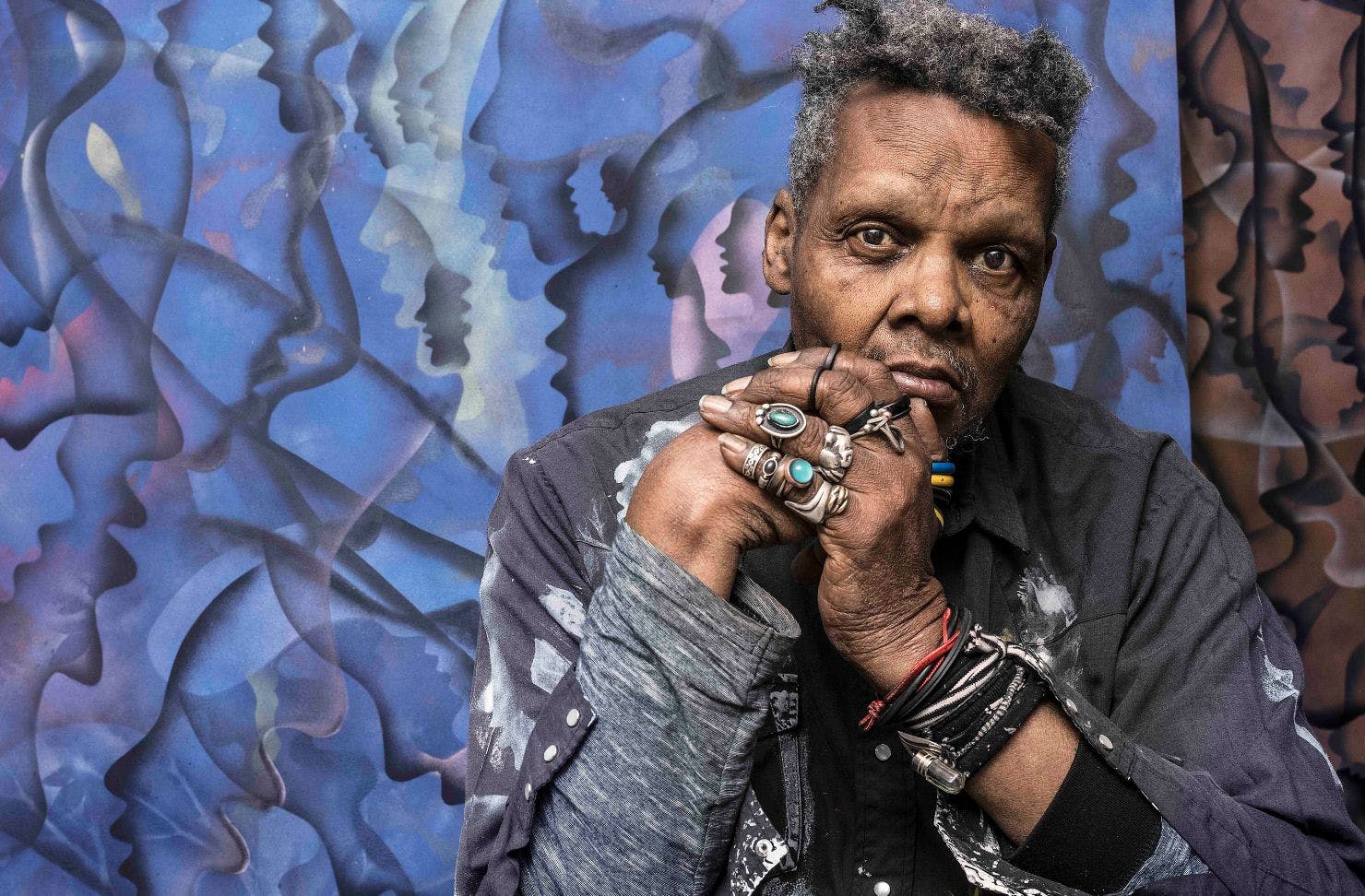 a person sitting and leaning against a graffitied wall