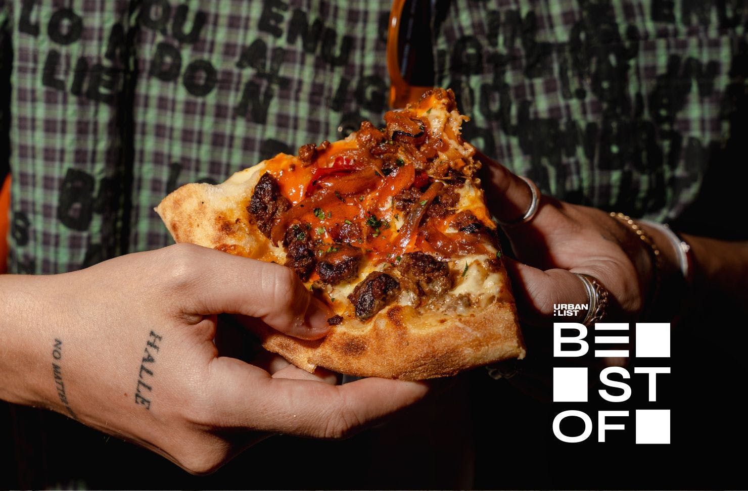tattooed hand holding a slice of pizza
