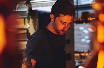 a person working situ in a restaurant kitchen with dim lit lighting