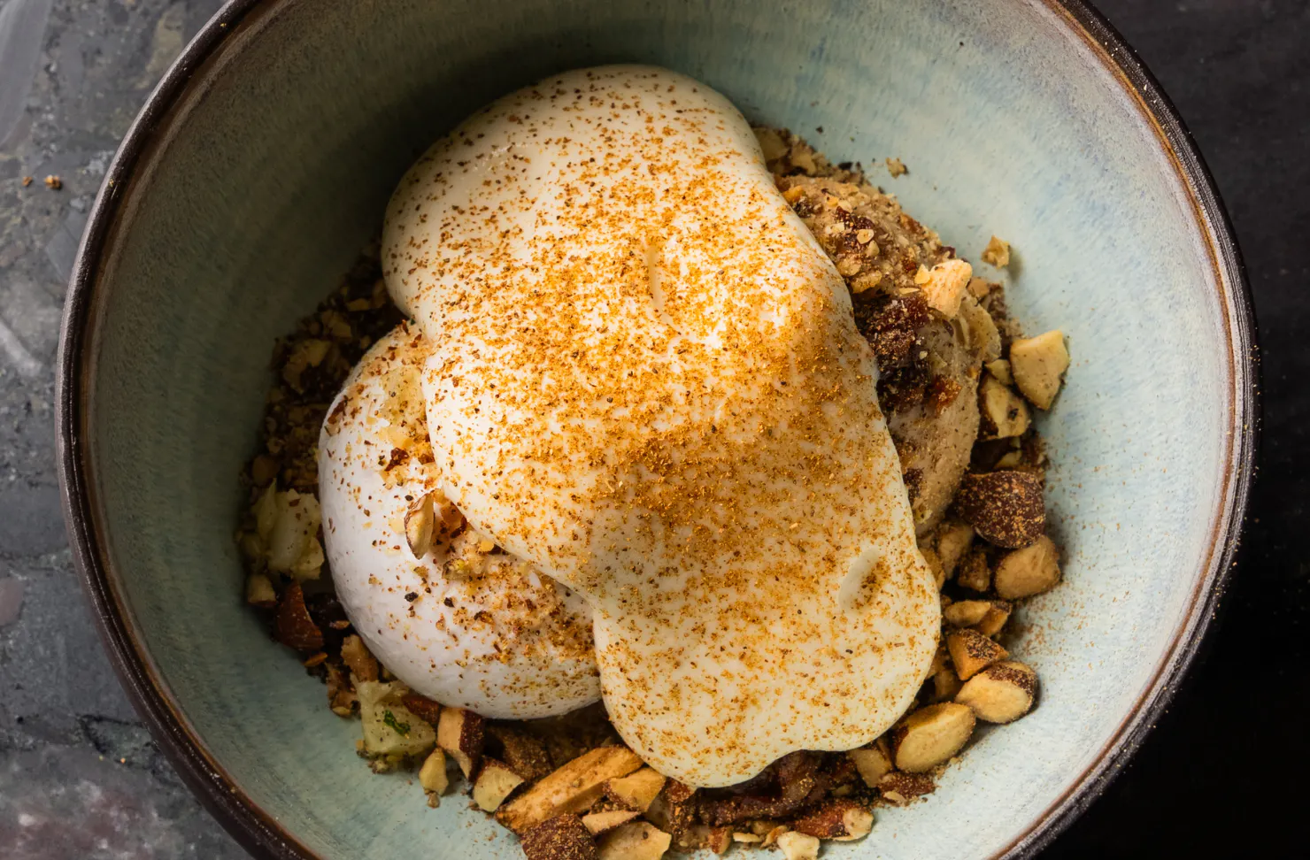 a plate filled with nuts, ice-cream and topped with custard