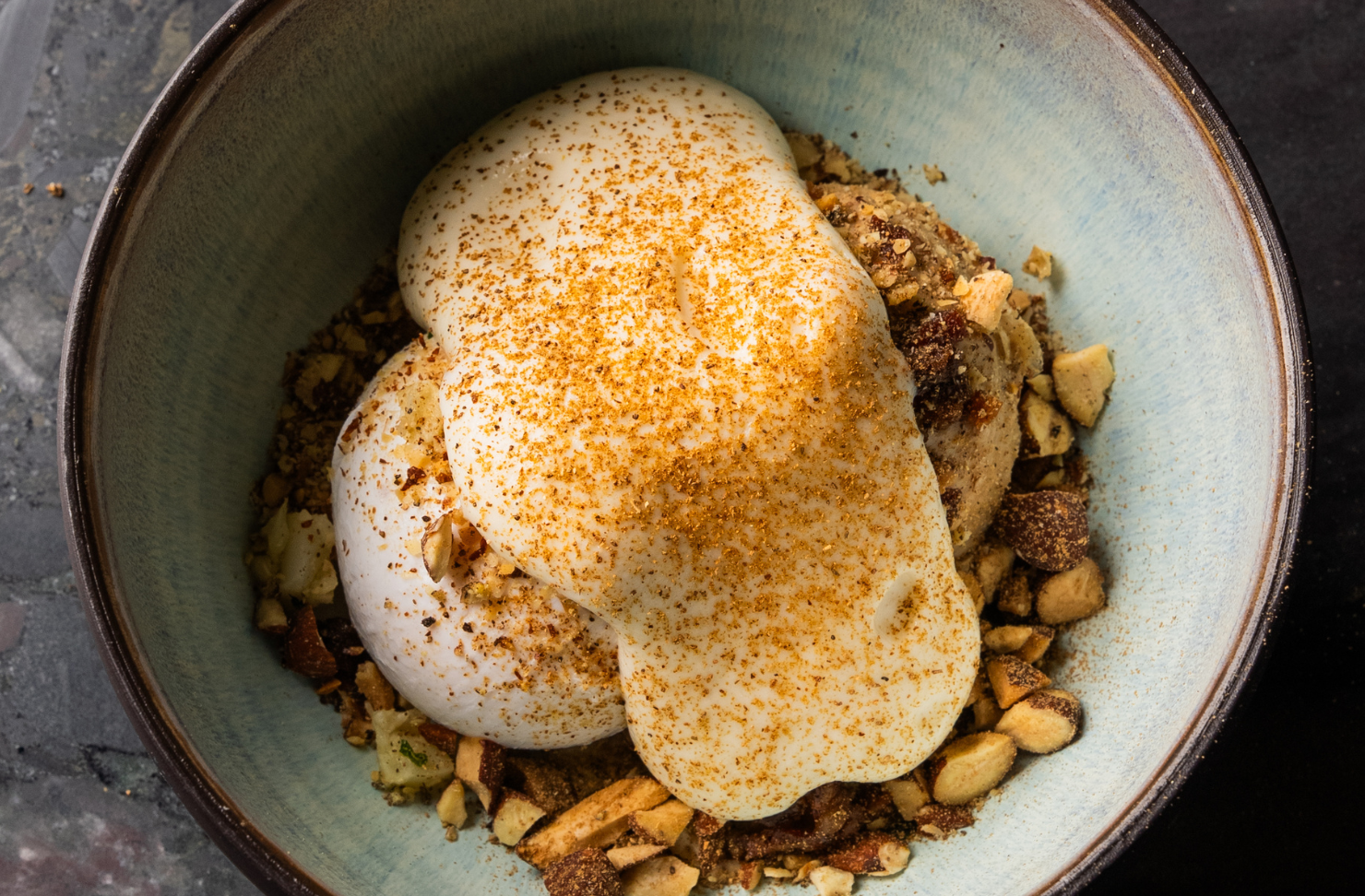 a plate filled with nuts, ice-cream and topped with custard