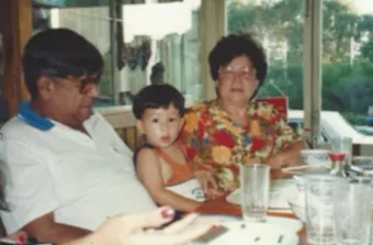 a slightly blurry archival of grandparents and son at a dinner table