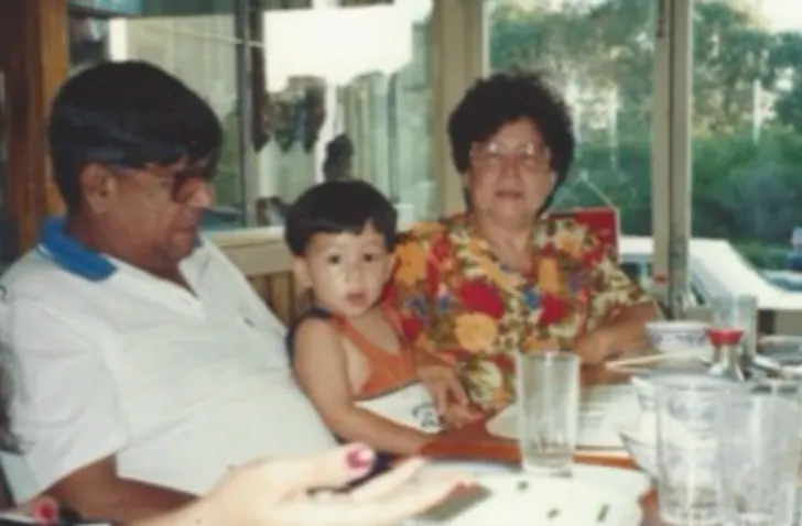 a slightly blurry archival of grandparents and son at a dinner table